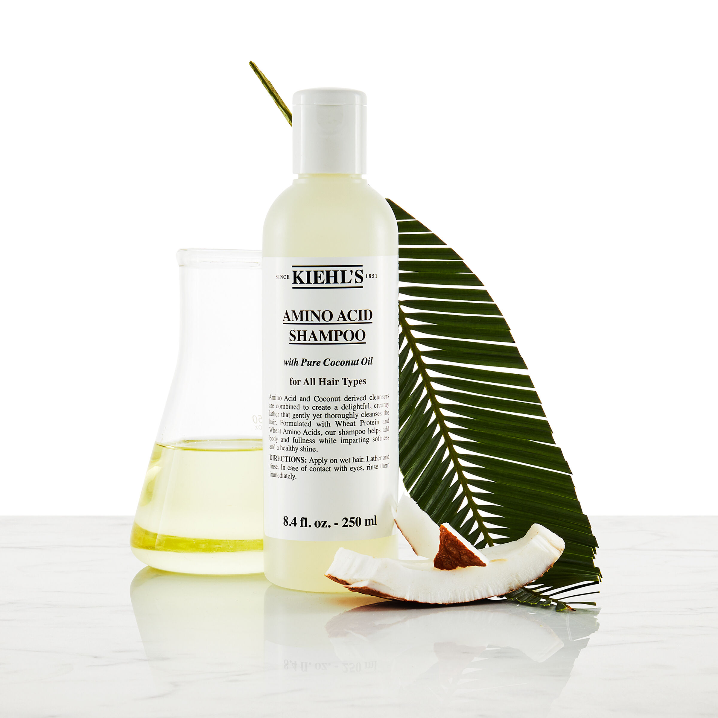 Model z wąsami i butelką szamponu Kiehl's Amino Acid Shampoo