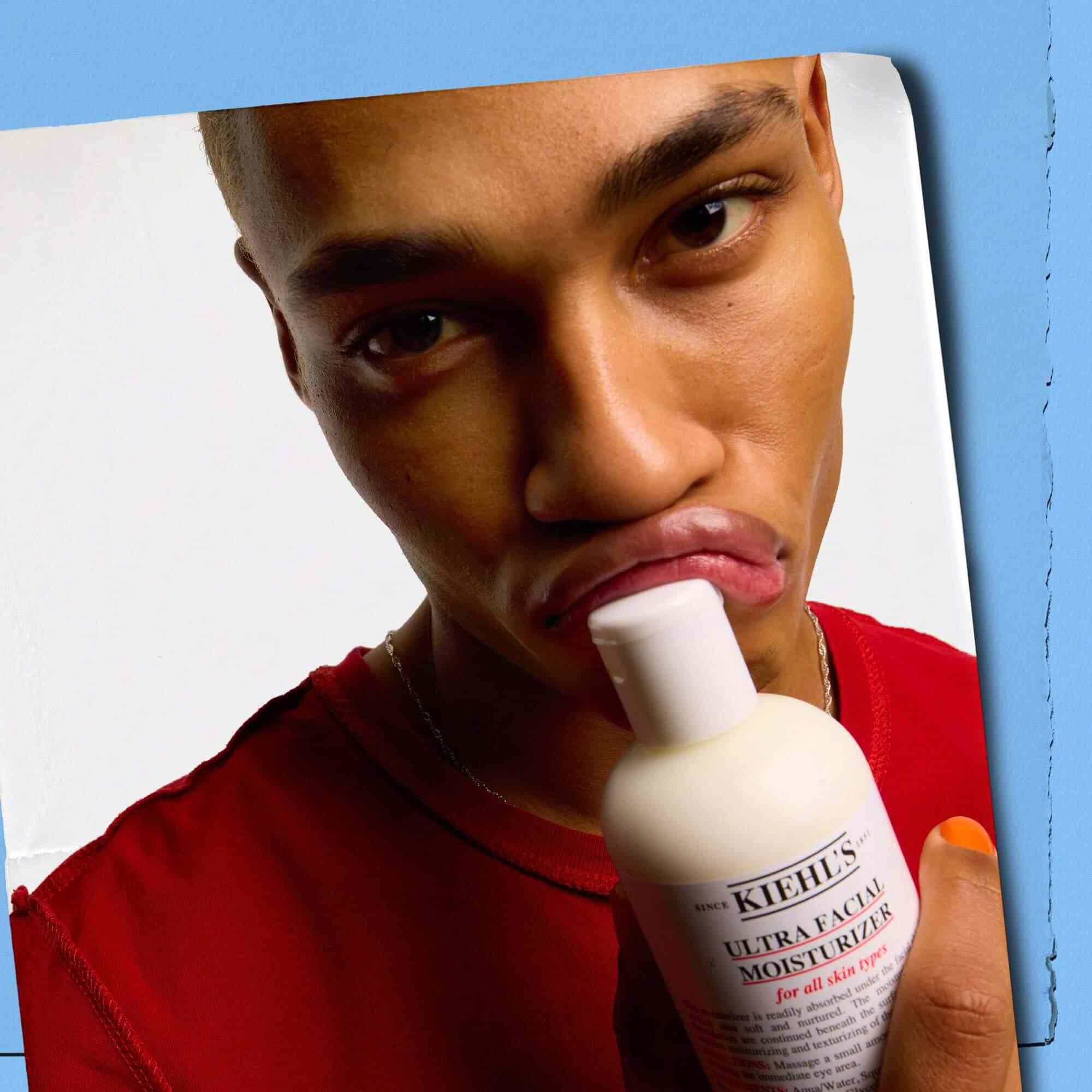 Modelka dociskająca butelkę Kiehl's Ultra Facial Moisturizer do ust