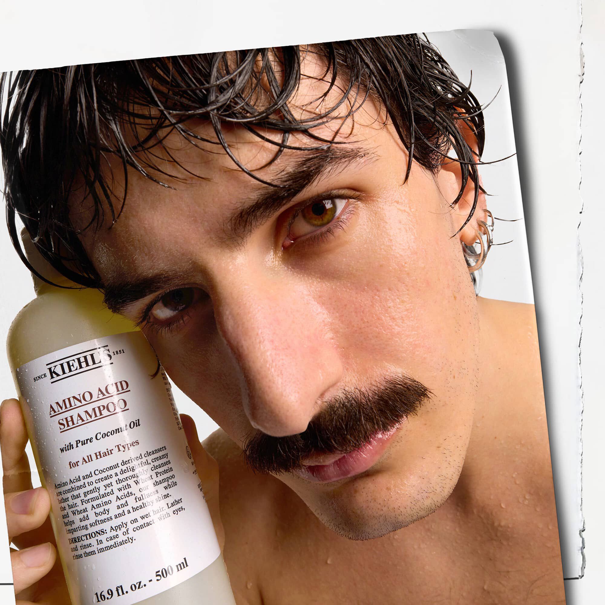 Model z wąsami i butelką szamponu Kiehl's Amino Acid Shampoo