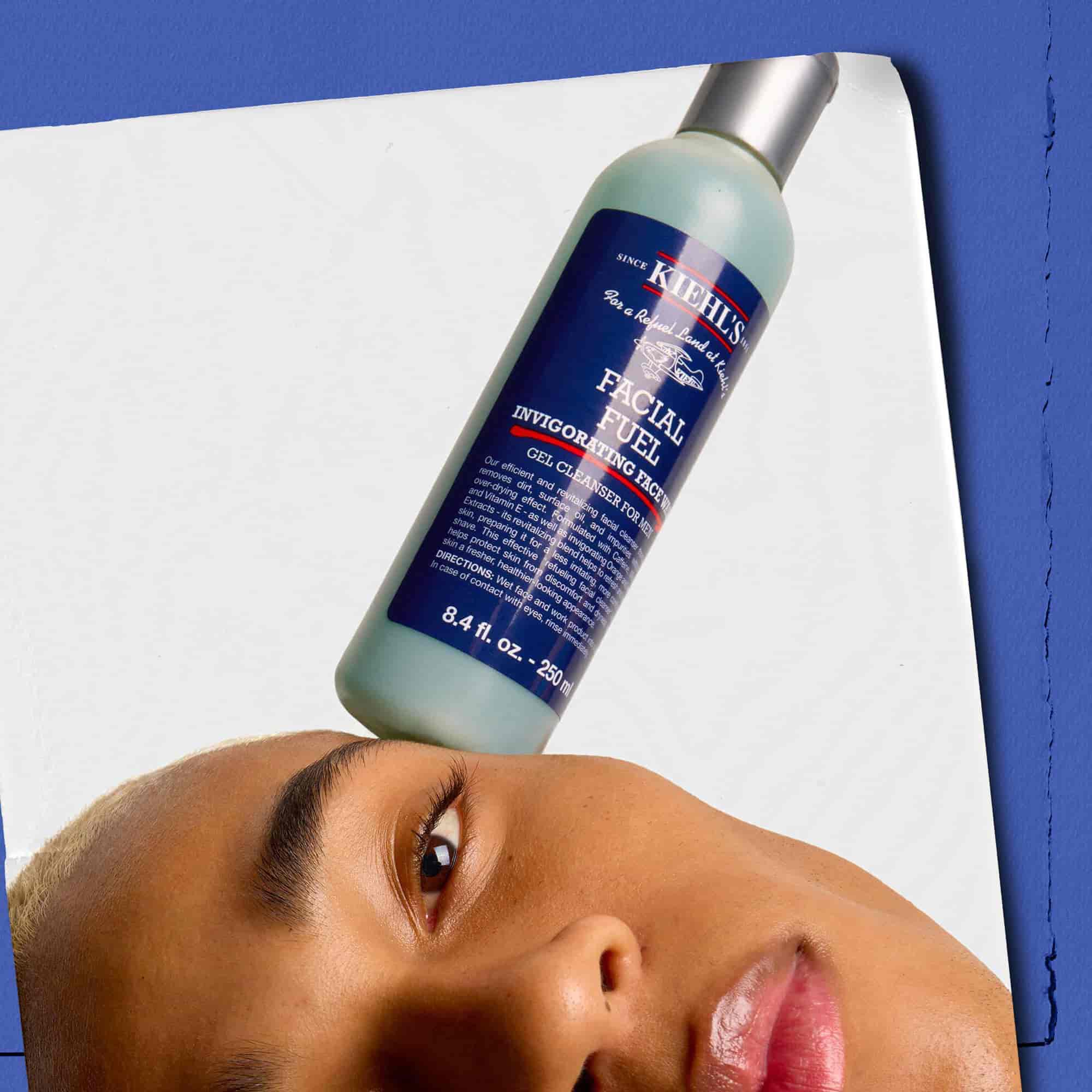 Model z butelką energetyzującego żelu do mycia twarzy Kiehl's Facial Fuel balansującą na twarzy