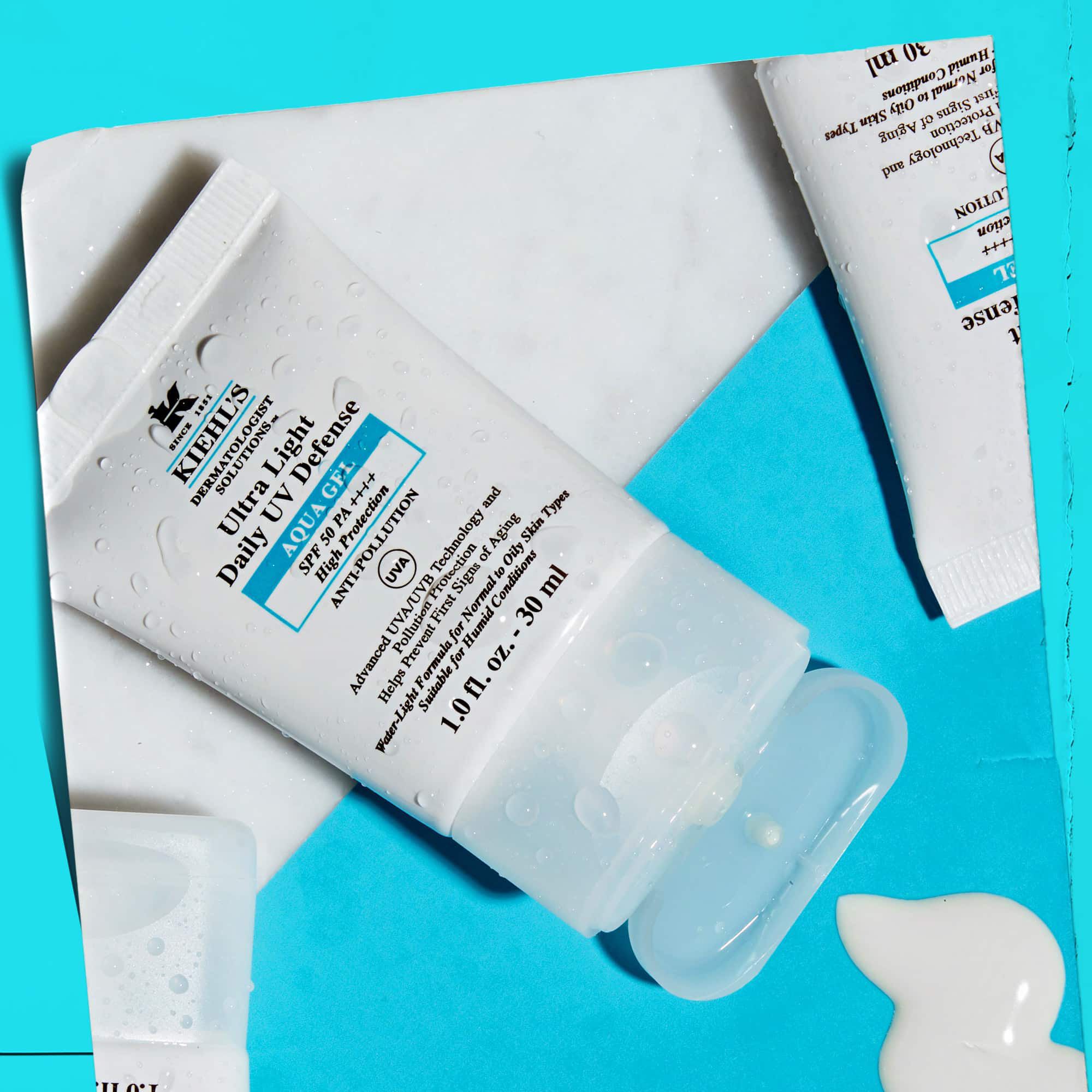 Układ flat-lay kilku tubek żelu Ultra Light Daily UV Defense Aqua Gel na marmurowej powierzchni, prezentujący ich lifestylowy charakter.