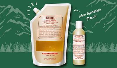 Image depicts a Kiehl's product featuring a refillable body cleanser pouch alongside a smaller bottle of the same cleanser. The background shows a nature-themed design with mountains, emphasizing eco-friendliness. Text highlights the pouch as a "New Refillable Pouch."