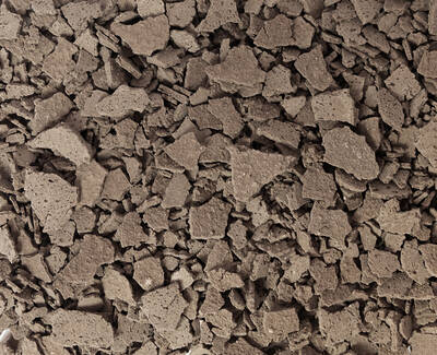A close-up view of a surface covered in irregularly shaped, light brown fragments resembling crushed materials or soil.