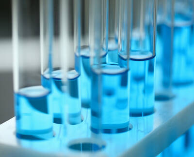 Close-up of test tubes filled with bright blue liquid, arranged in a rack with a soft focus on the background.