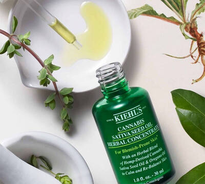 Butelka zielonego oleju konopnego Kiehl's na tle liści, z pipetą do aplikacji. Idealna na problemy skorne.