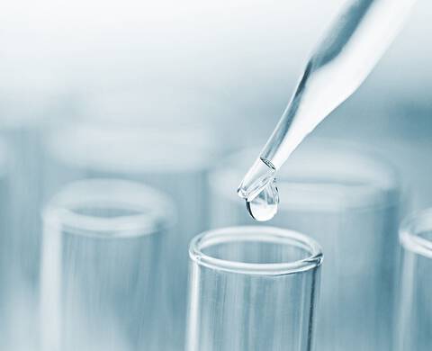 Kropla substancji spadająca z pipety do probowki.