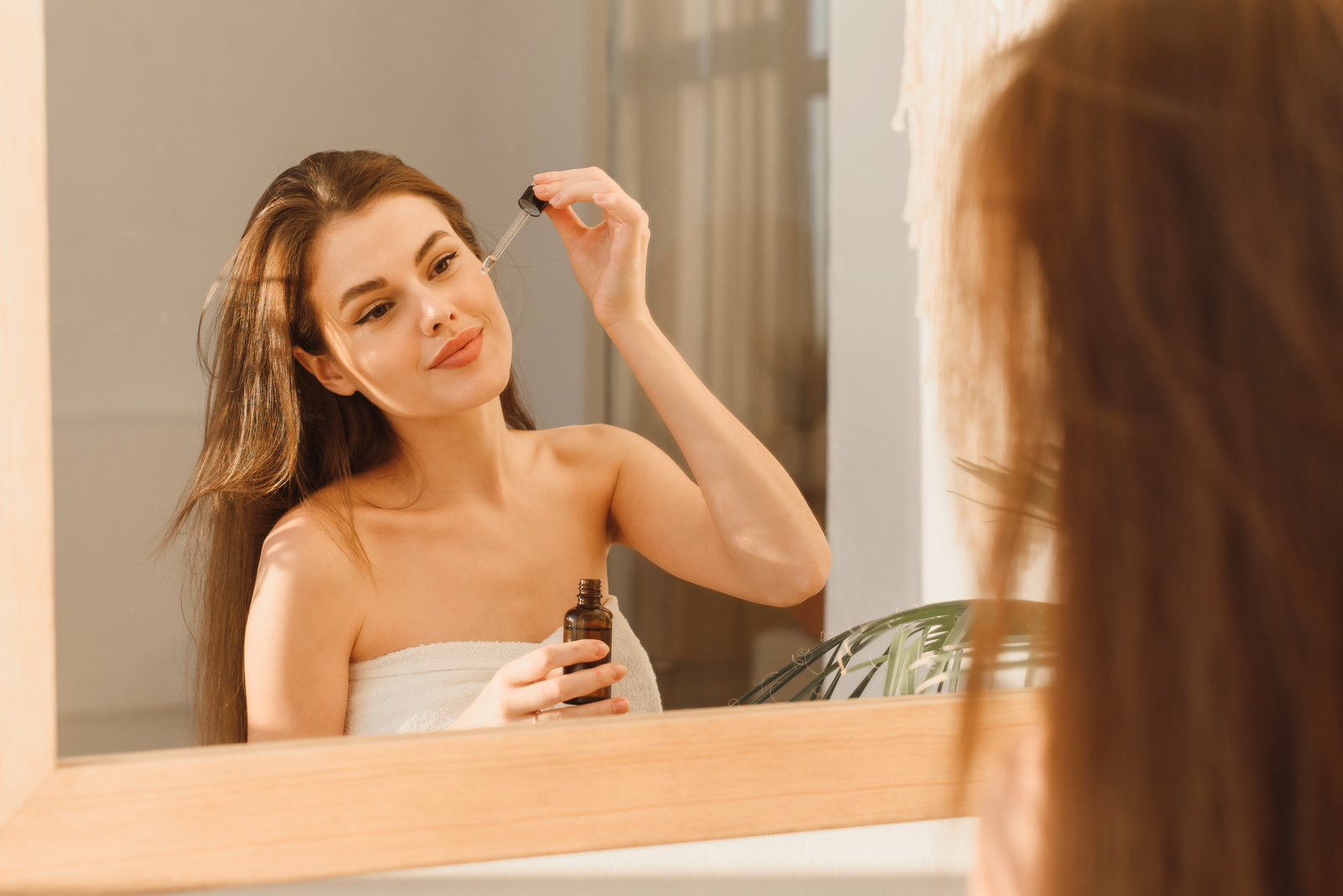  Kobieta nakładająca przed lustrem serum na twarz