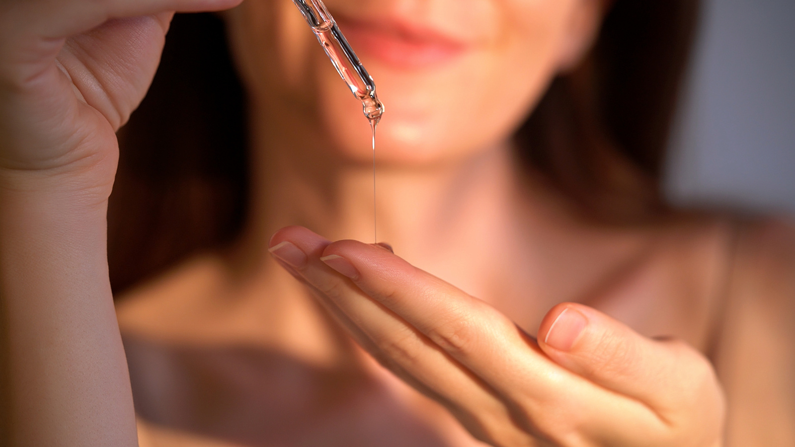 Uśmiechnięta kobieta nakładająca serum na dłoń