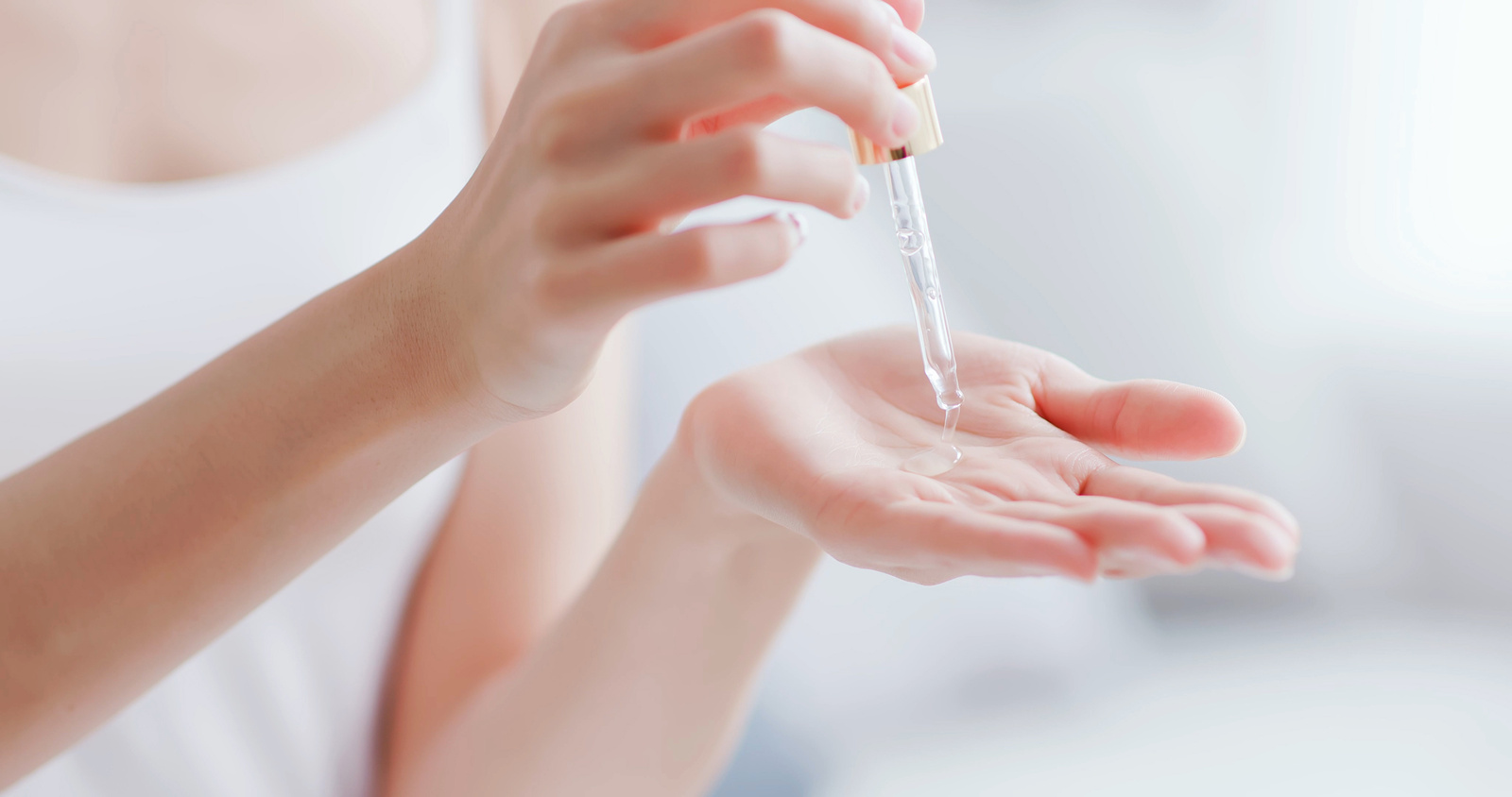 Kobieta aplikuje na swoją dłoń kropkę serum z peptydami